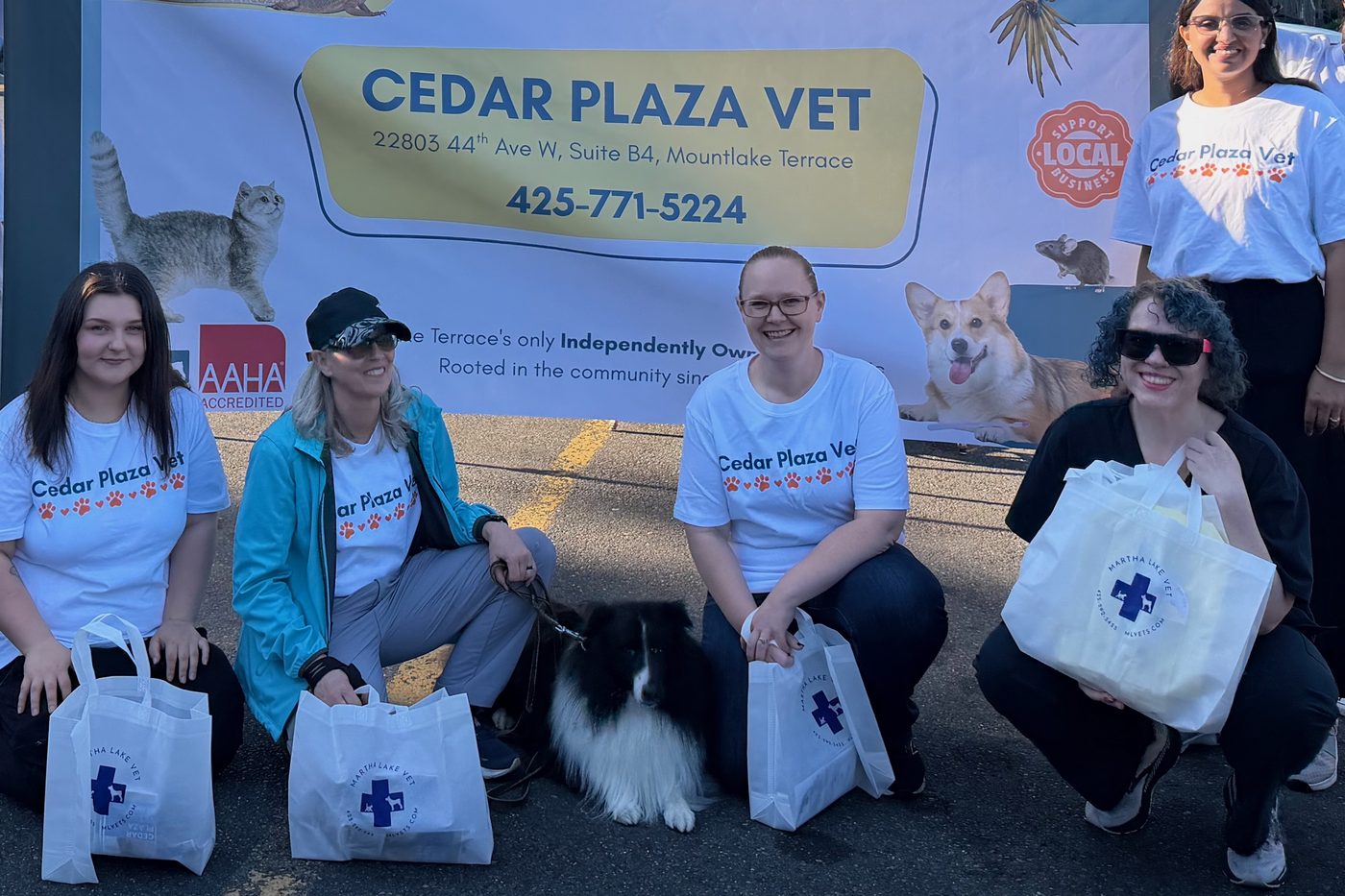 Our team in Cedar Plaza Vet T-shirts, with a clinic dog, in front of the Cedar Plaza Vet banner at a Mountlake Terrace community event